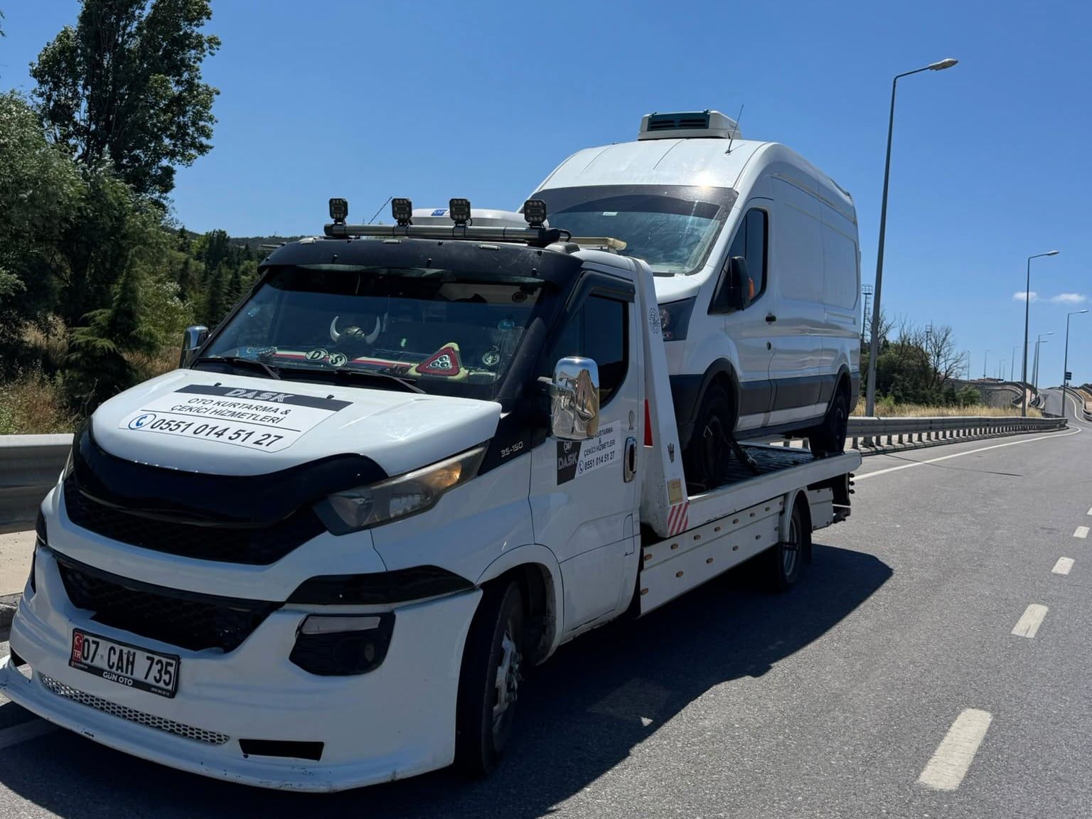 Yolda ilerleyen Dask Oto Kurtarma çekicisi; kaputta 0551 014 51 27 numarası